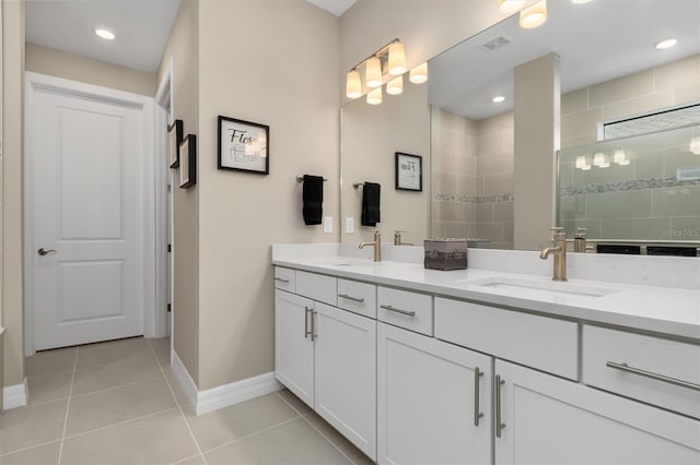 bathroom featuring a tile shower, baseboards, a sink, and tile patterned floors