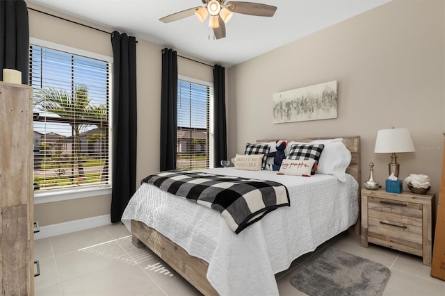 bedroom featuring light tile patterned floors, multiple windows, and baseboards