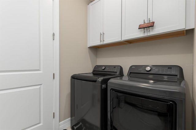 clothes washing area with cabinet space, washing machine and dryer, and baseboards