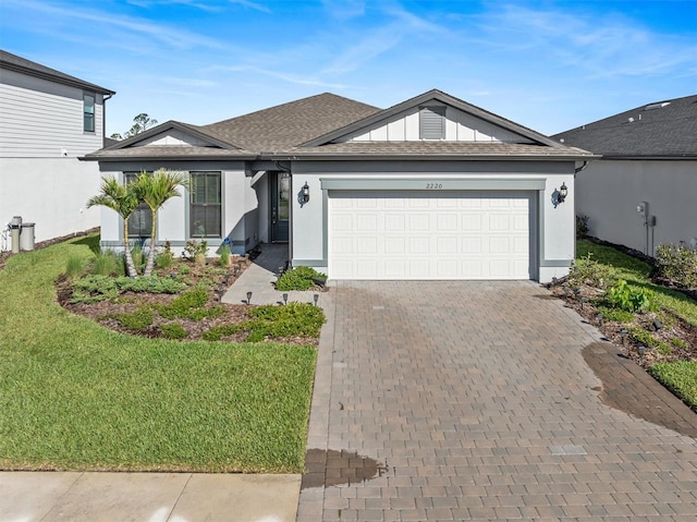 ranch-style house with decorative driveway, roof with shingles, stucco siding, an attached garage, and a front lawn