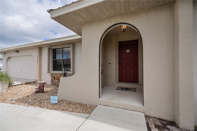 entrance to property with a garage and stucco siding