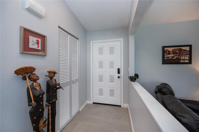 entryway featuring baseboards, an AC wall unit, and light colored carpet