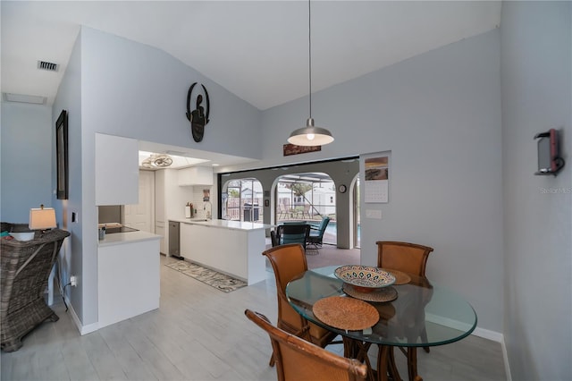 dining area featuring lofted ceiling, light wood-style floors, baseboards, and visible vents