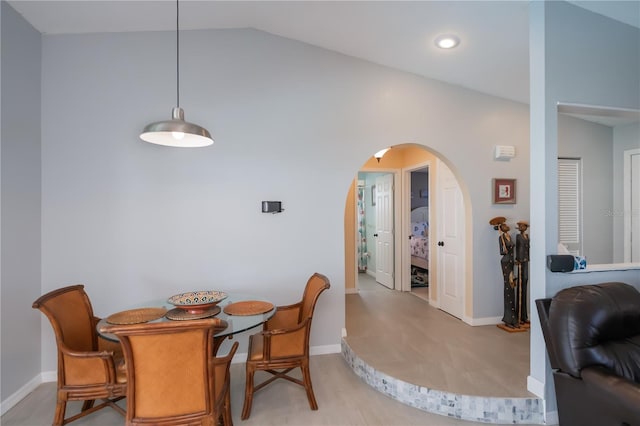 dining space with lofted ceiling, baseboards, and arched walkways