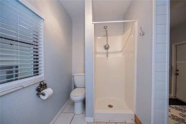 bathroom with toilet, a shower stall, baseboards, and tile patterned flooring