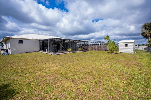 view of yard featuring a lanai, fence, a storage unit, and an outdoor structure