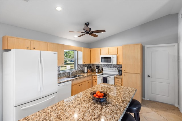 kitchen with lofted ceiling, white appliances, light brown cabinets, and a sink