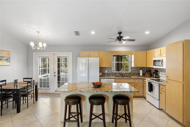 kitchen with lofted ceiling, light brown cabinetry, white appliances, and french doors