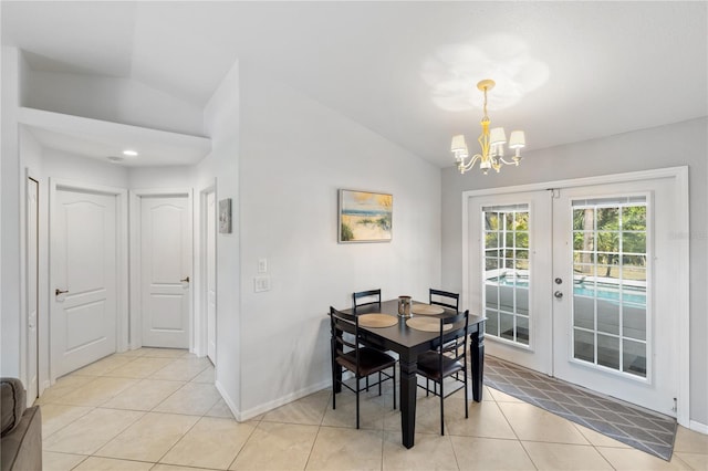 dining space with lofted ceiling, french doors, light tile patterned floors, and a notable chandelier