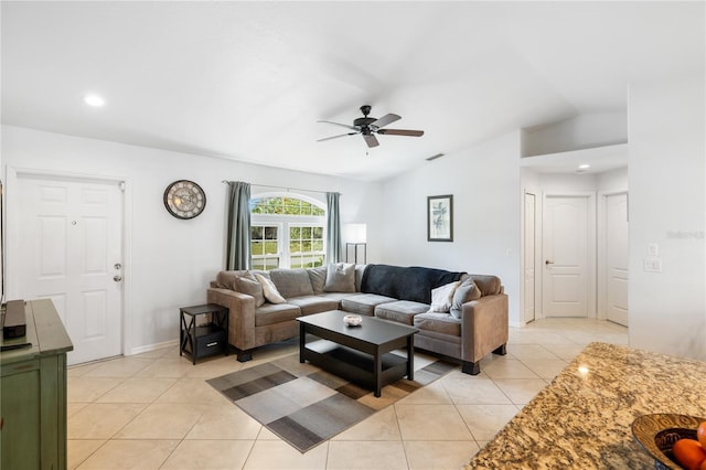 living area featuring light tile patterned floors, visible vents, baseboards, ceiling fan, and vaulted ceiling