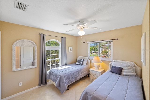 bedroom featuring a ceiling fan, light tile patterned flooring, visible vents, and multiple windows