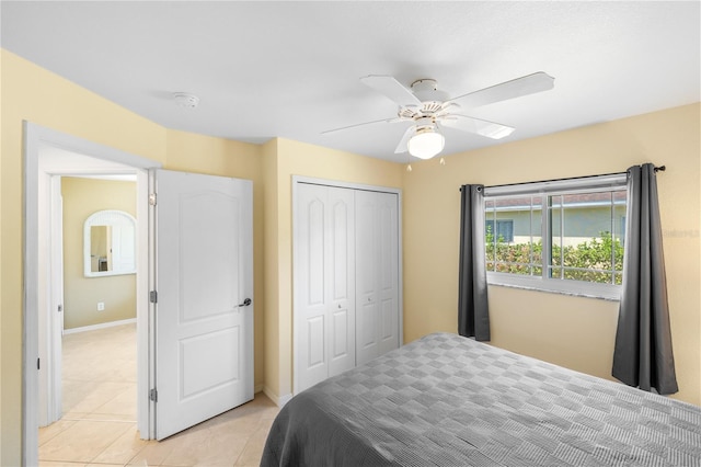 bedroom featuring light tile patterned floors, baseboards, a ceiling fan, and a closet