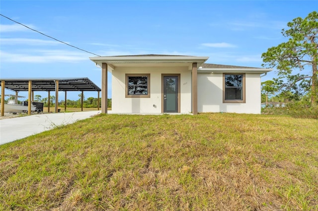 view of front of property with a detached carport, a front yard, concrete driveway, and stucco siding