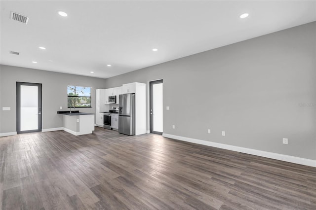 kitchen with dark countertops, visible vents, open floor plan, stainless steel appliances, and white cabinetry