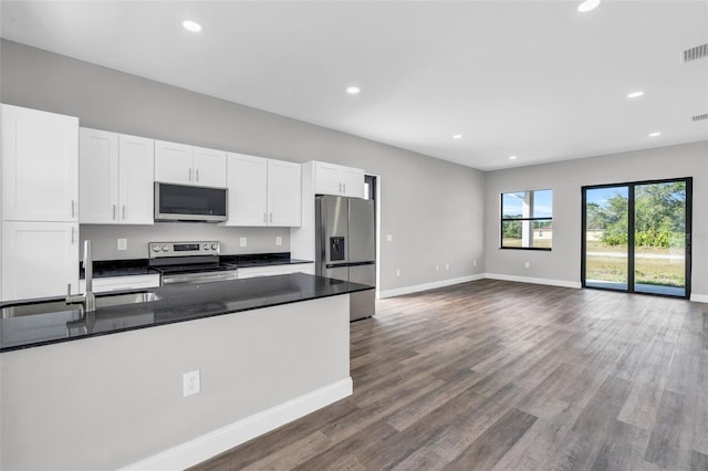 kitchen with dark countertops, recessed lighting, appliances with stainless steel finishes, white cabinets, and a sink