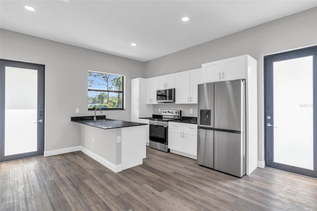 kitchen with dark countertops, white cabinets, a peninsula, and stainless steel appliances