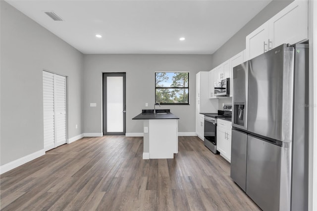 kitchen featuring dark countertops, dark wood-style floors, stainless steel appliances, white cabinets, and baseboards