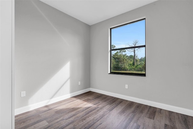 spare room with baseboards and wood finished floors