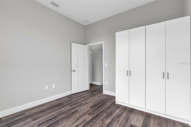 unfurnished bedroom featuring baseboards, visible vents, and dark wood-style flooring