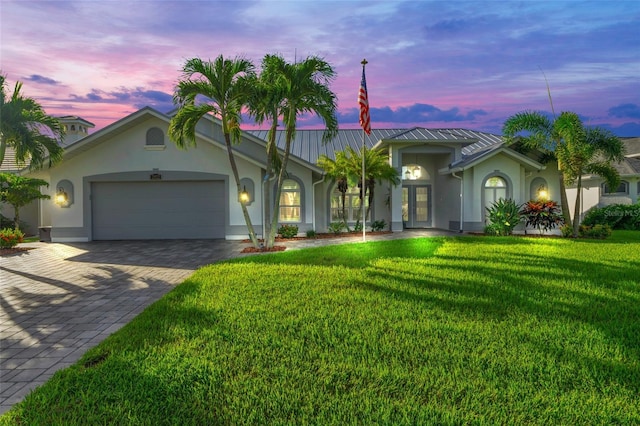 view of front of house featuring a garage, a front yard, decorative driveway, and stucco siding