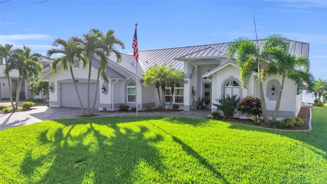 view of front facade featuring metal roof, an attached garage, stucco siding, a front lawn, and a standing seam roof