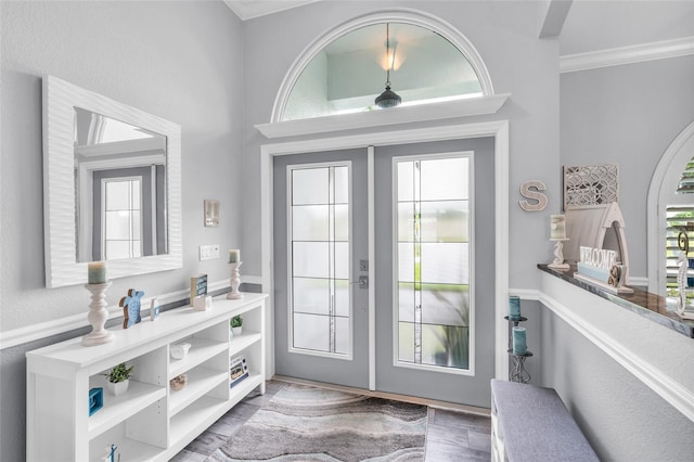 entryway with french doors, wood finished floors, and crown molding