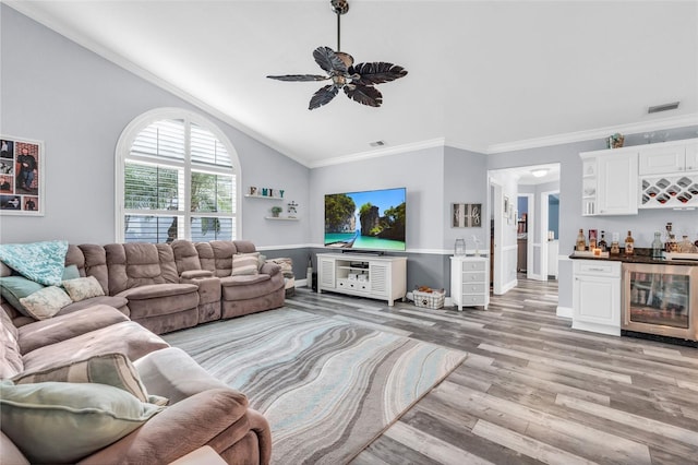 living area featuring light wood finished floors, a dry bar, visible vents, ornamental molding, and beverage cooler