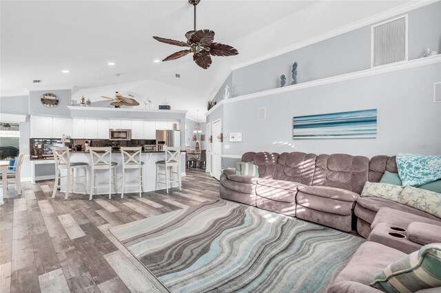 living room featuring high vaulted ceiling, recessed lighting, a ceiling fan, light wood-type flooring, and crown molding