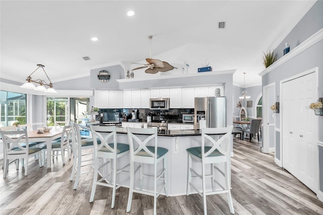 kitchen with stainless steel appliances, lofted ceiling, ornamental molding, and decorative backsplash