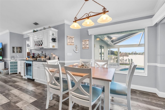 dining room with a dry bar, beverage cooler, visible vents, and ornamental molding