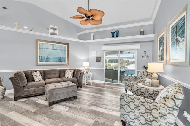 living area featuring visible vents, ornamental molding, vaulted ceiling, wood finished floors, and baseboards