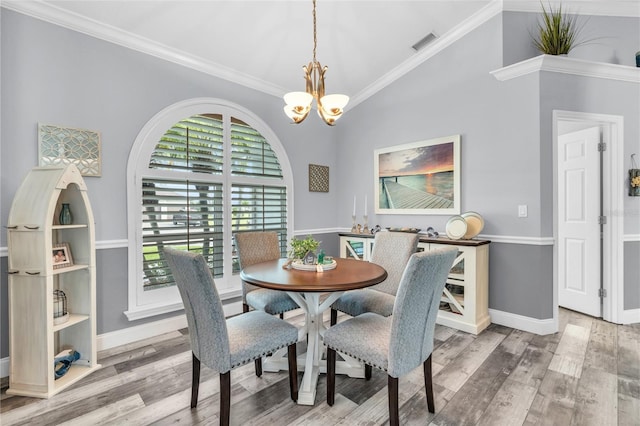 dining room featuring ornamental molding, wood finished floors, visible vents, and an inviting chandelier