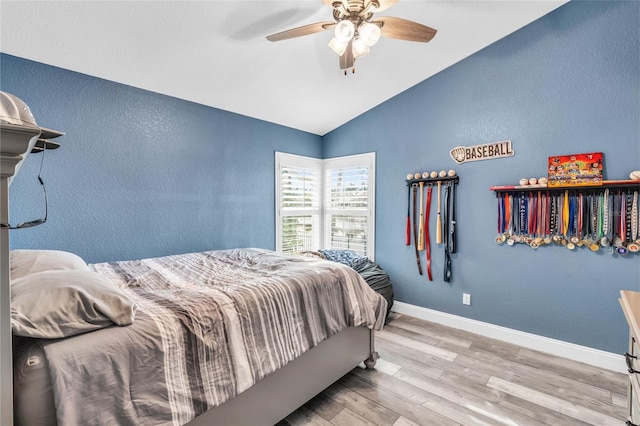 bedroom with baseboards, a ceiling fan, a textured wall, lofted ceiling, and wood finished floors