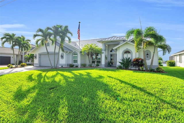 view of front of property featuring concrete driveway, stucco siding, metal roof, a standing seam roof, and a front yard