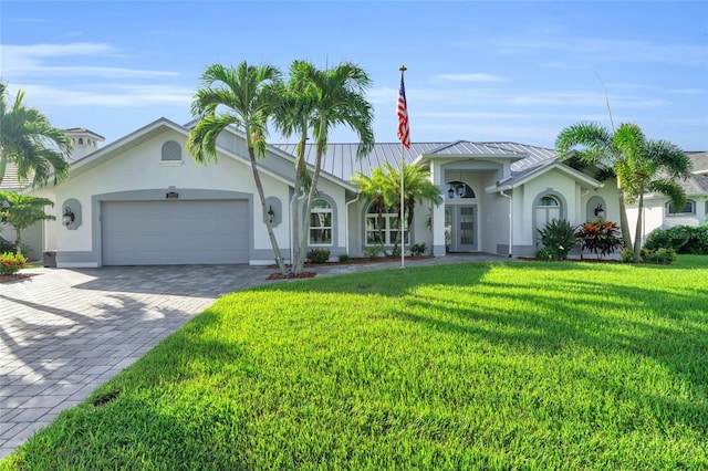 view of front of house featuring a garage, decorative driveway, metal roof, and stucco siding