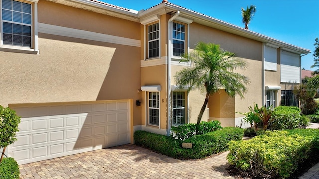 view of front of property with a garage, decorative driveway, and stucco siding