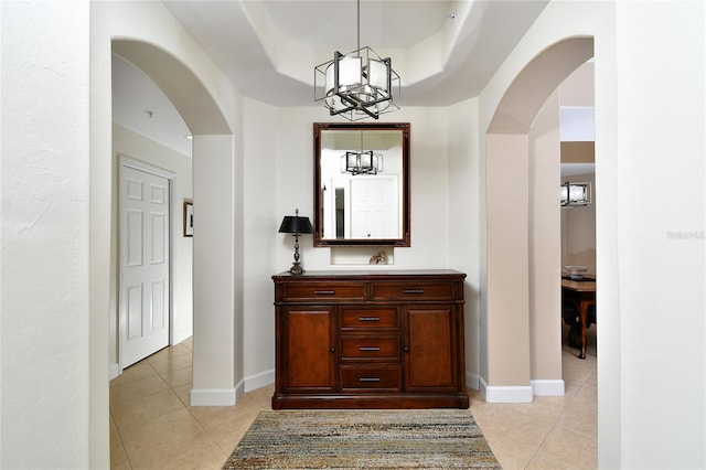 corridor with baseboards, arched walkways, and light tile patterned flooring