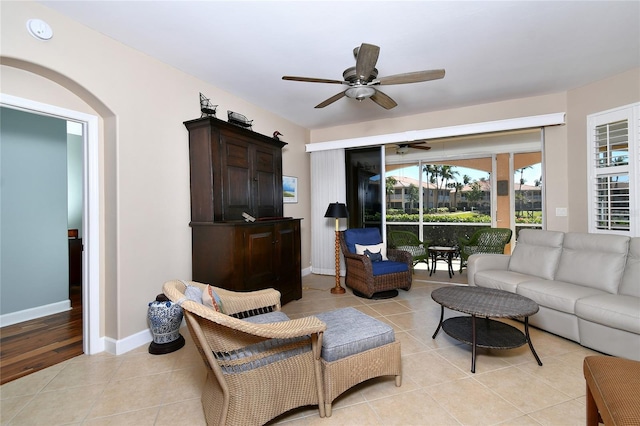 living area featuring light tile patterned floors, ceiling fan, and baseboards