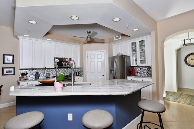 kitchen with white cabinets, a tray ceiling, stainless steel appliances, and light tile patterned flooring