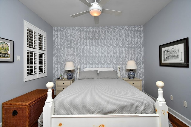 bedroom featuring an accent wall, baseboards, and a ceiling fan