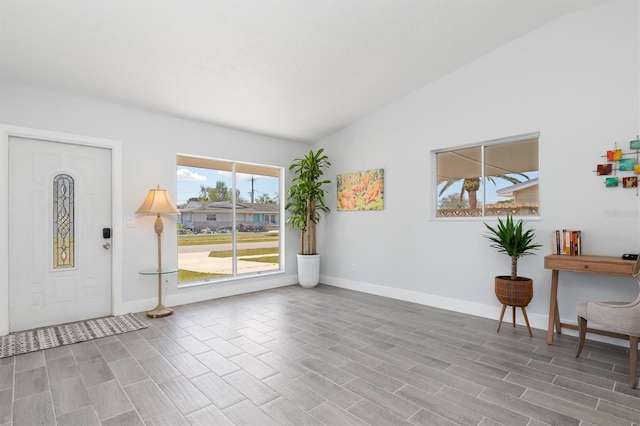 entryway featuring lofted ceiling, wood finished floors, and baseboards