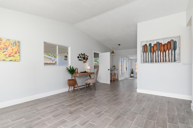 interior space with plenty of natural light, baseboards, vaulted ceiling, and wood finished floors