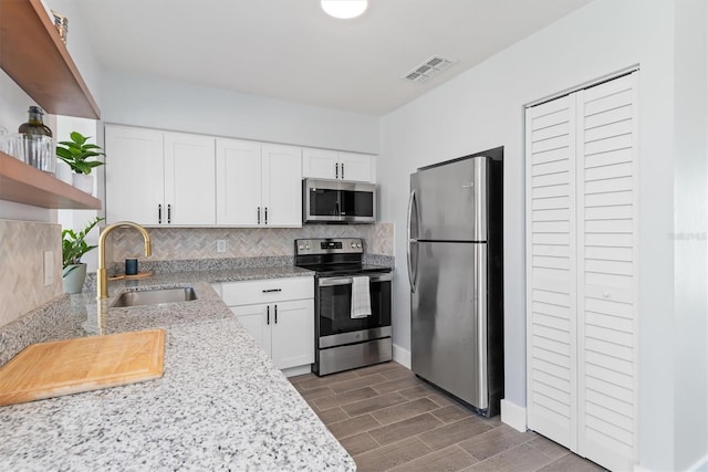 kitchen with stainless steel appliances, a sink, visible vents, open shelves, and tasteful backsplash