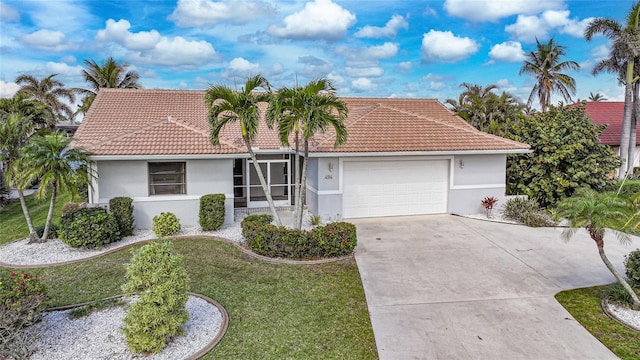 view of front of property with a tile roof, stucco siding, a front yard, a garage, and driveway