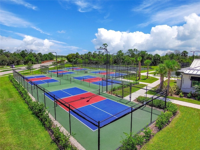 view of tennis court with fence and a lawn