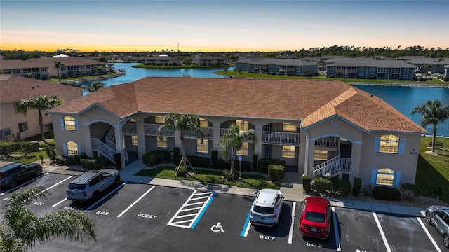 view of building exterior featuring uncovered parking, a water view, and a residential view