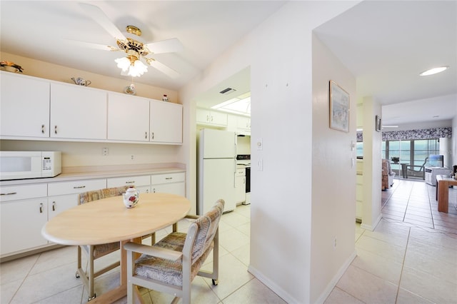 kitchen featuring light tile patterned floors, white appliances, white cabinets, baseboards, and light countertops