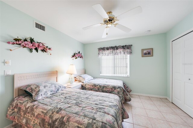 bedroom with a closet, visible vents, a ceiling fan, tile patterned flooring, and baseboards