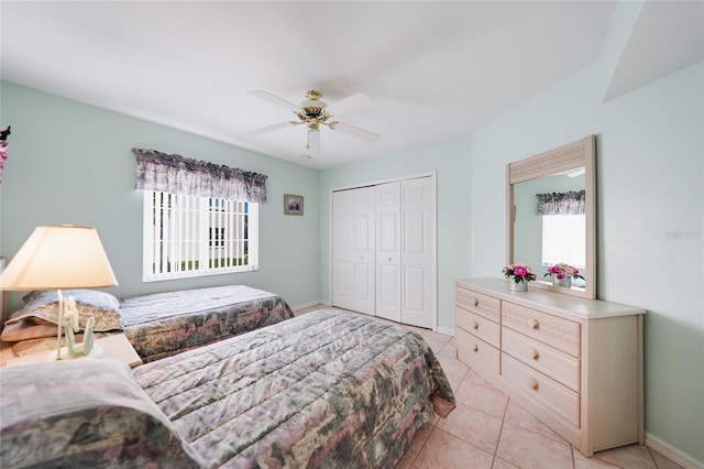 bedroom with light tile patterned floors, a closet, a ceiling fan, and baseboards