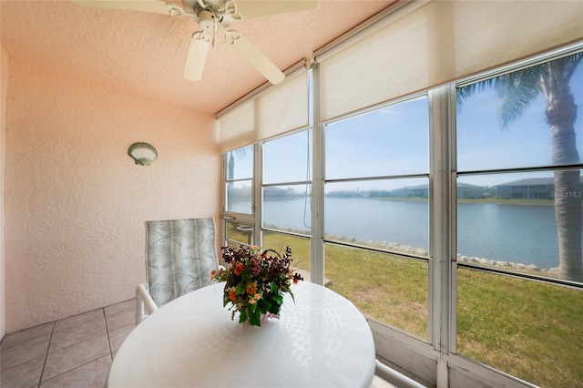 sunroom featuring ceiling fan, a water view, and a healthy amount of sunlight